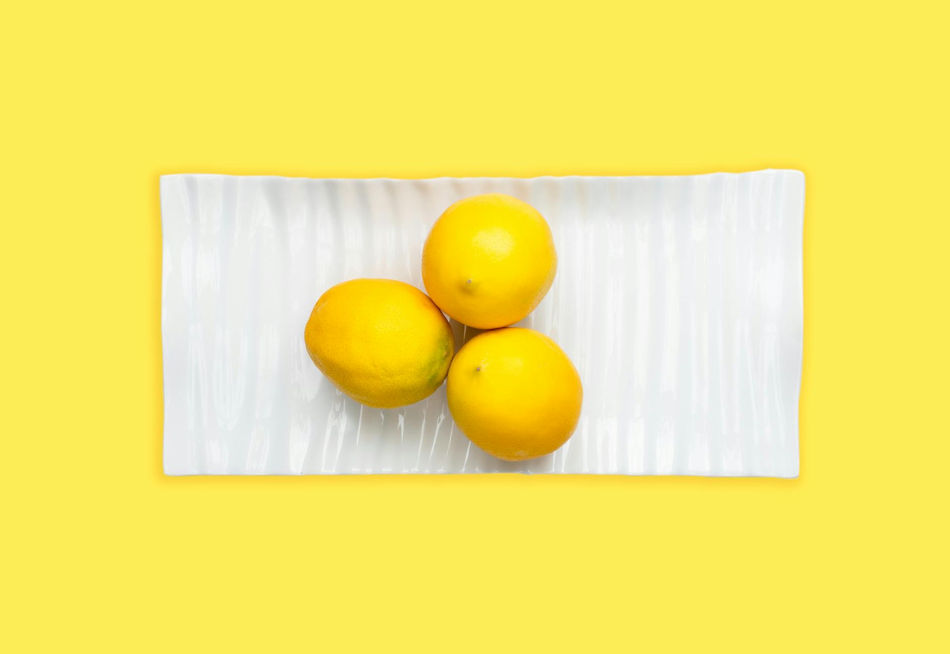 Fresh lemons on white plate, representing citrus-inspired sensation and pleasure design