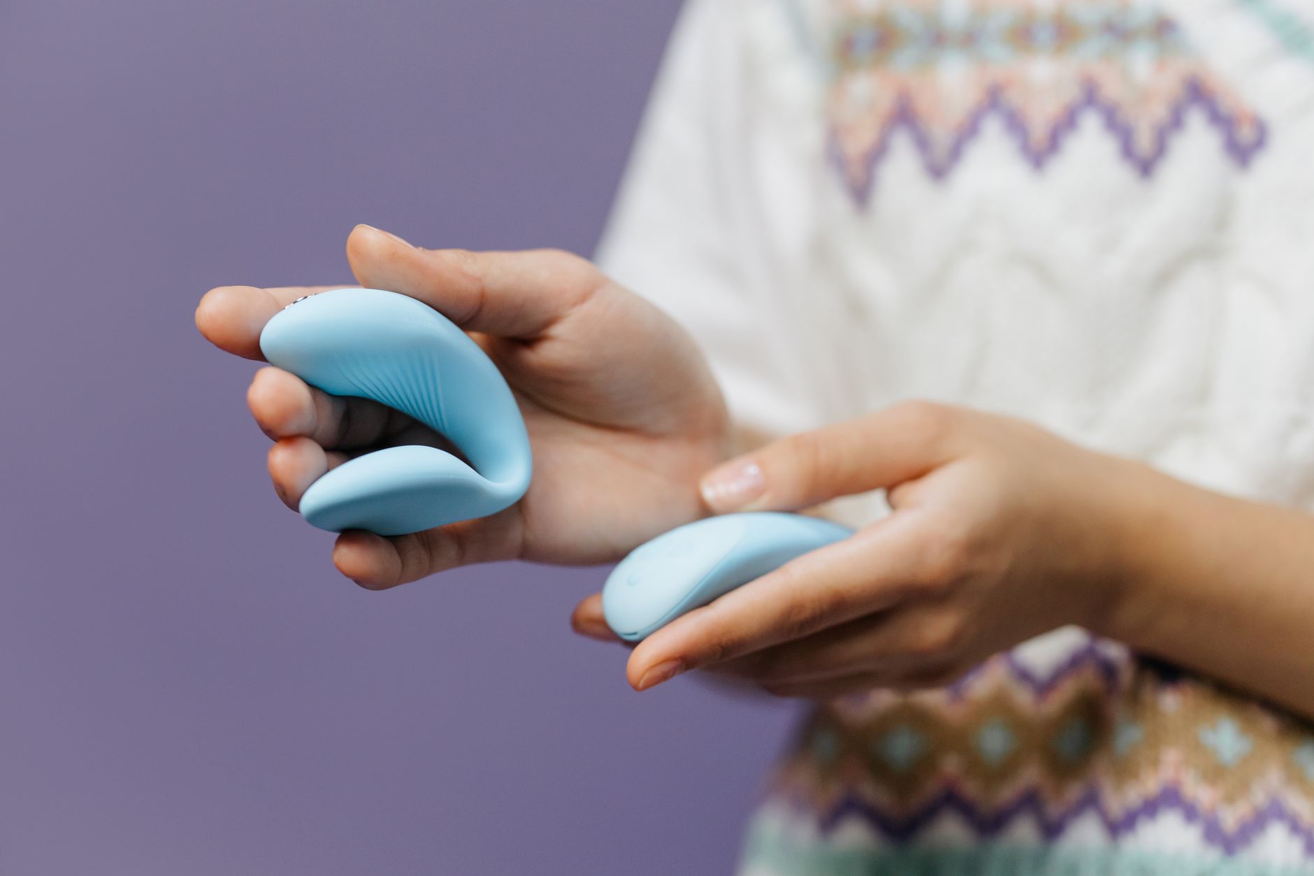 Hand holding a lemon vibrator against a purple background