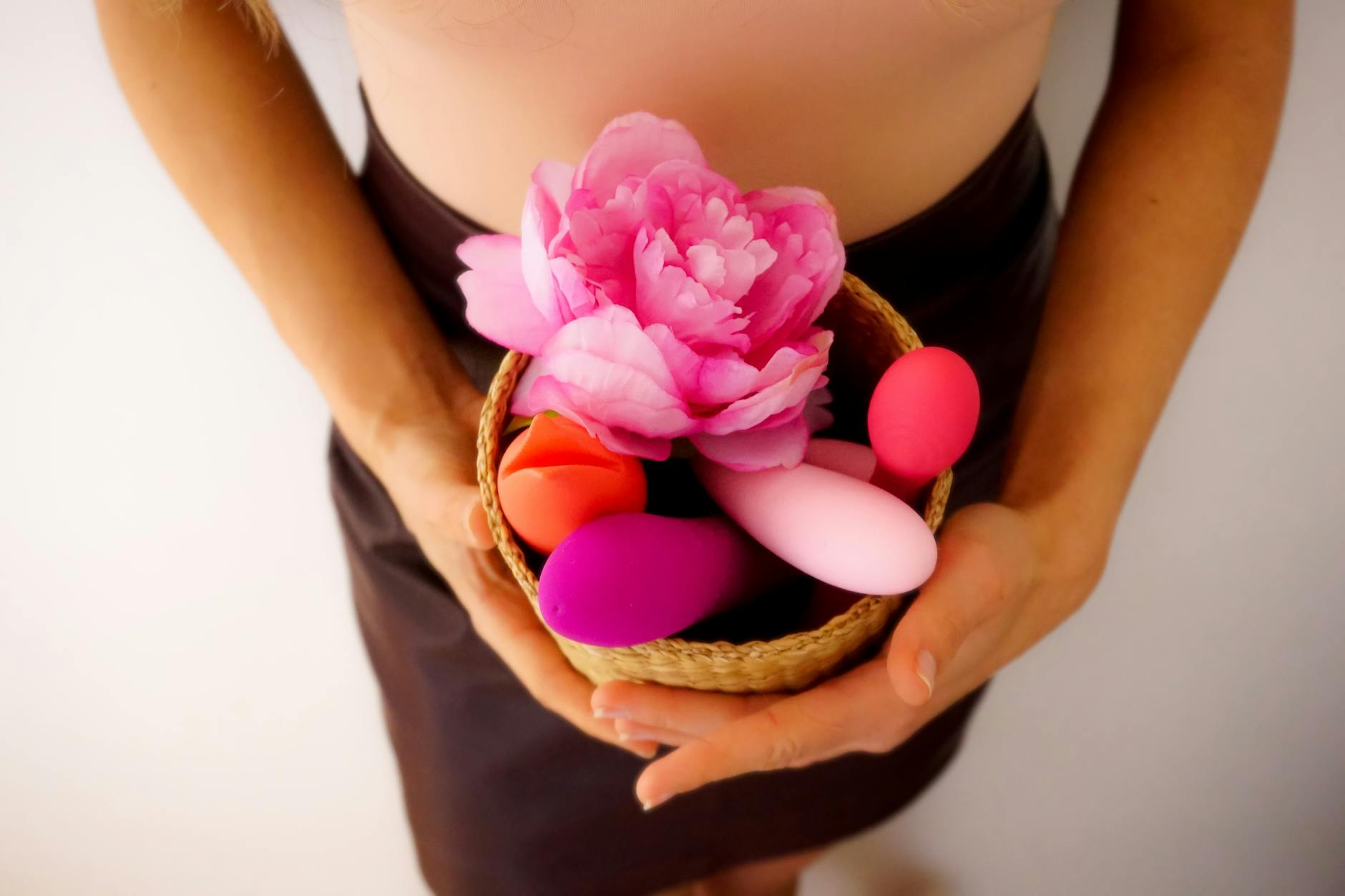 Close-up of a hand holding an orange vibrator against a minimalistic purple backdrop, showcasing modern sensuality